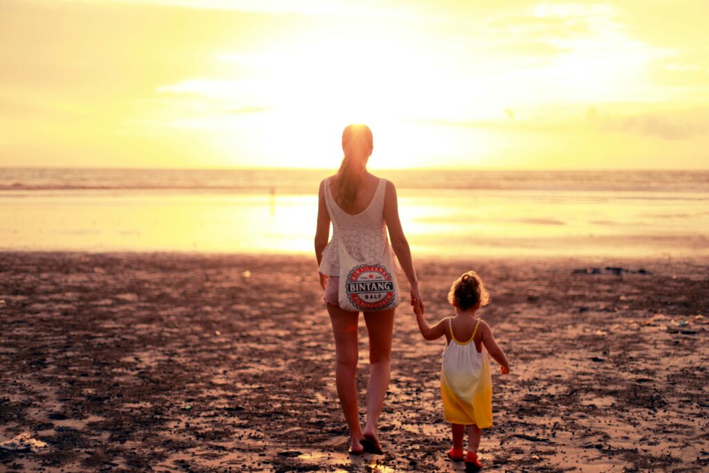 Vrouw met kind op het strand, tijdens de zonsondergang