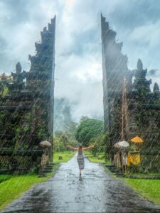 dame in de regen bij Balinese tempelpoort