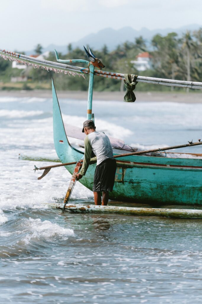 visser bij bootje op het strand bij Amed Bali